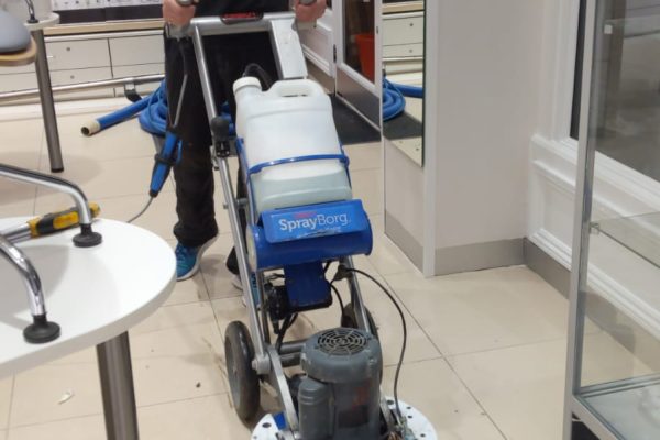 Team member using the Hos Orbot cleaning system to restore the shop floor tiles at Boots Opticians, London Wall.